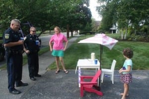 Officer Ronald Alley, left, and Officer William Higgins stop at a homemade lemonade stand to support a young entrepreneur 